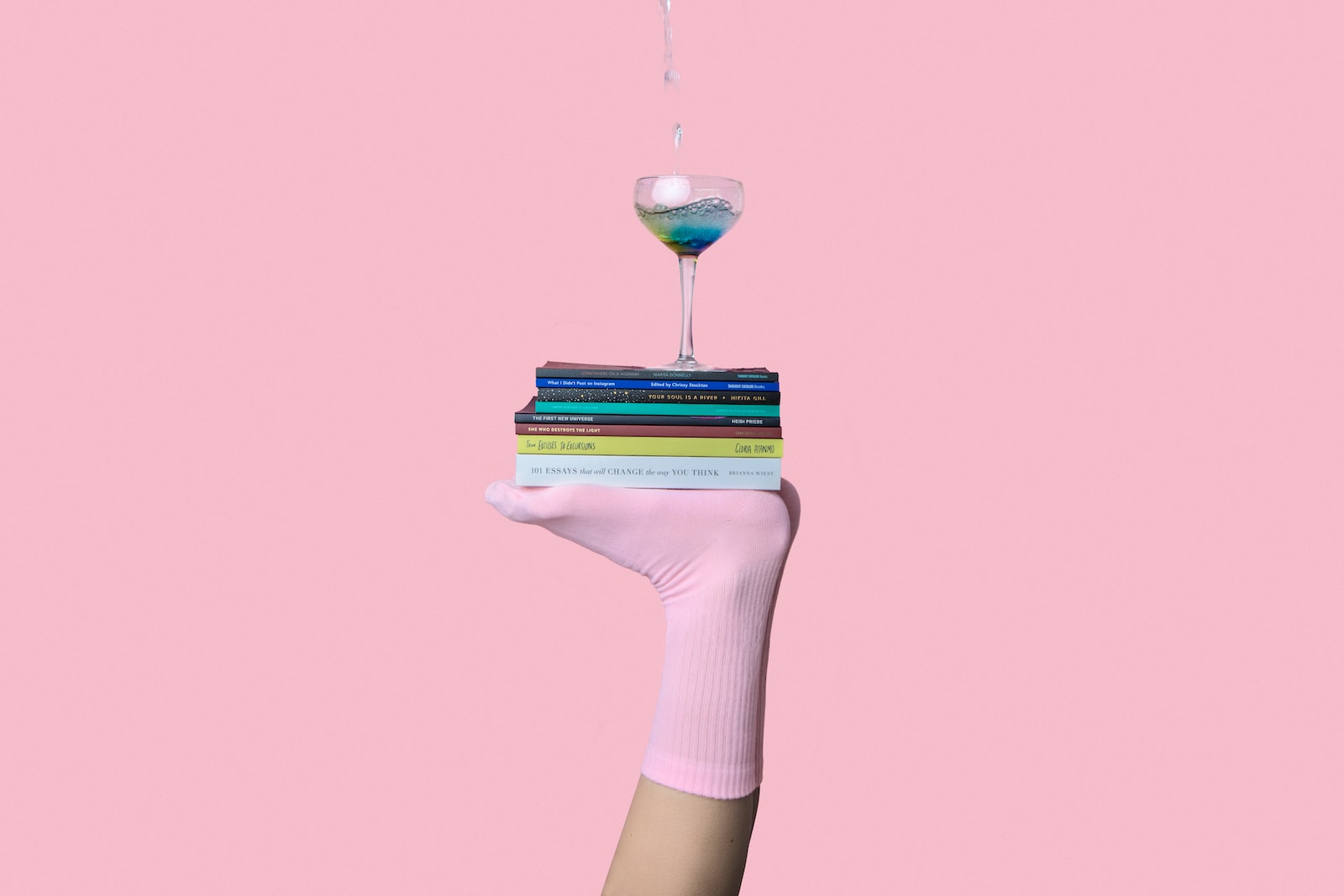 person balancing glass above book with feet